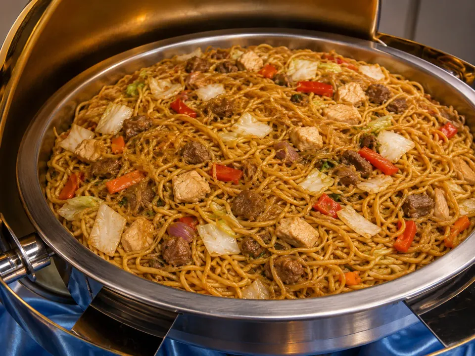 Pancit Canton with noodles, chicken, beef, and vegetables in a chafing dish